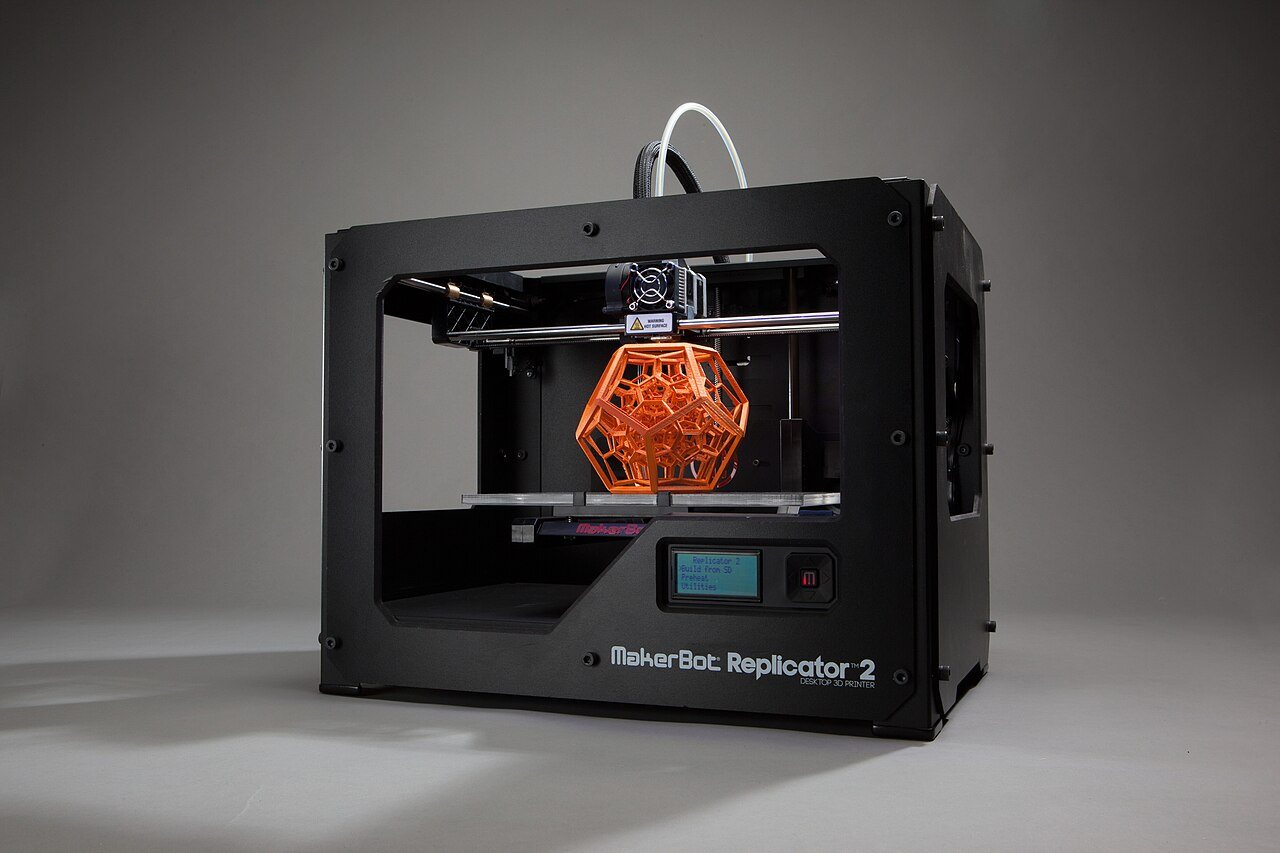 An FDM 3D printer finishing an orange printed part on the build plate
