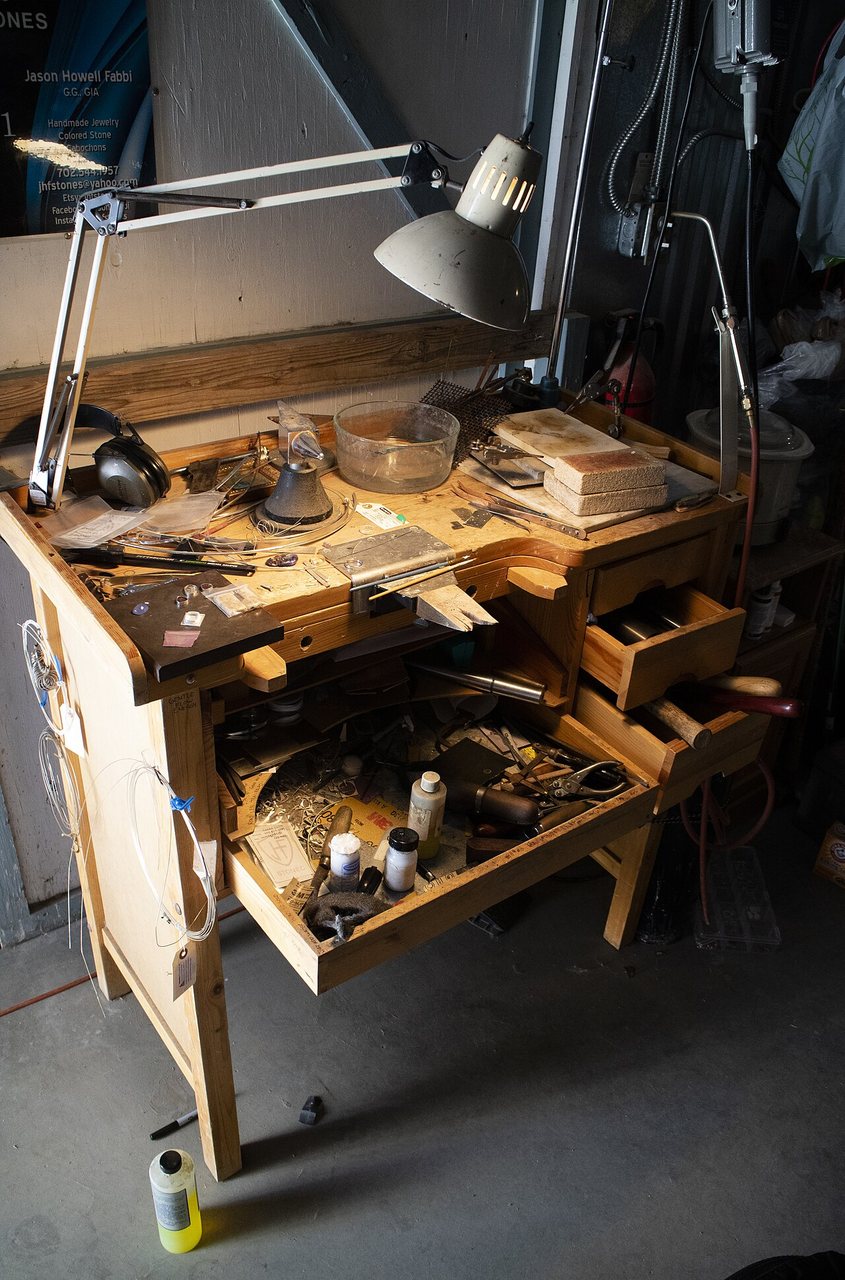 A wooden hobby workbench with drawers, hand tools and a lamp clamped to the front